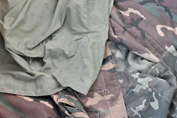 Camouflage background texture as backdrop for army and military design projects. Back side of soldiers camouflage jacket with many pleats on crumpled fabric