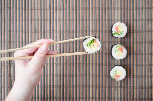 Una Mano Con Bacchette Tiene Rotolo Sushi Uno Sfondo Paglia — Foto Stock