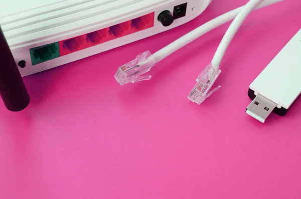 Internet router, portable USB wi-fi adapter and internet cable plugs lie on a bright pink background. Items required for internet connection