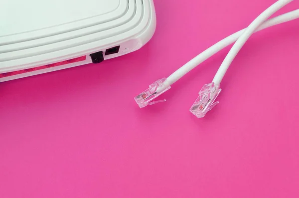 Internet router and Internet cable plugs lie on a bright pink background. Items required for Internet connection