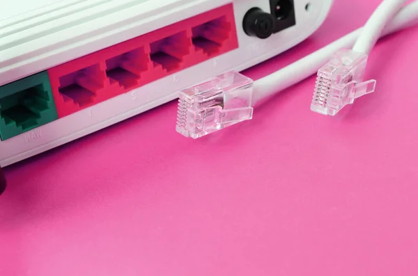 Internet router and Internet cable plugs lie on a bright pink background. Items required for Internet connection