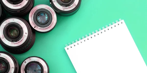 Több Fényképészeti Lencse Fehér Notebook Fekszik Egy Fényes Türkiz Háttér — Stock Fotó