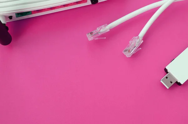 Internet router, portable USB wi-fi adapter and internet cable plugs lie on a bright pink background. Items required for internet connection