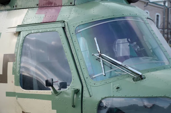 Close up view on helicopter cabin fragment. Camouflage aircraft fuselage and bulletproof glass