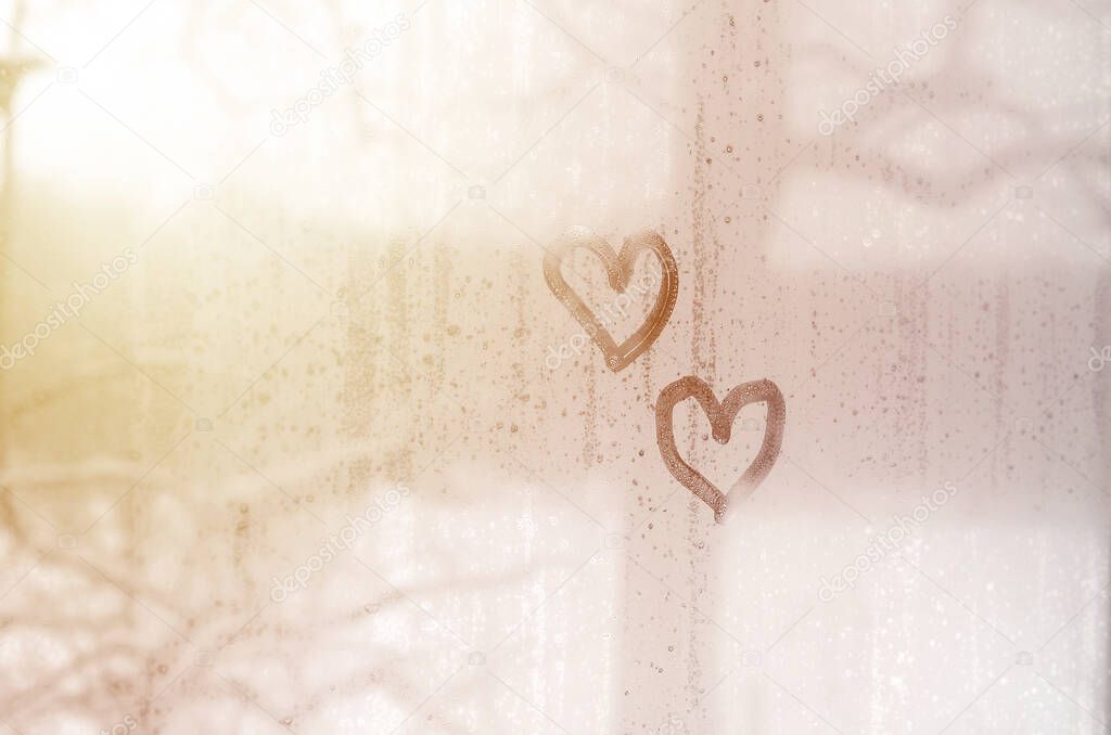Two hearts painted on a misted glass in the winter