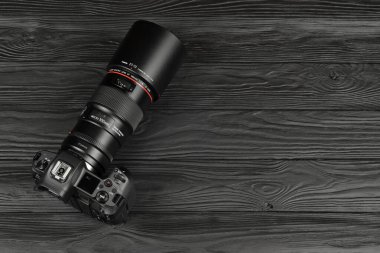 KHARKOV, UKRAINE - NOVEMBER 23, 2020: Canon EOS R fotoğraf makinesi ve adaptör EF - EOS R 'yi Canon 105mm f2.8 lensli siyah ahşap masaya monte edin. Fotoğraf ekipmanları: Canon Inc..
