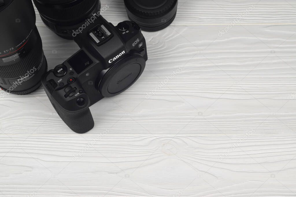 KHARKOV, UKRAINE - NOVEMBER 23, 2020: Canon EOS R photocamera and mount adapter EF - EOS R with Canon 105mm f2.8 and Sigma 24-105 f4 Art lenses on white wooden table