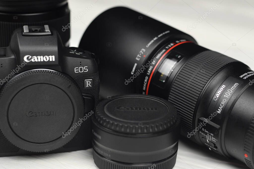 KHARKOV, UKRAINE - NOVEMBER 23, 2020: Canon EOS R photocamera and mount adapter EF - EOS R with Canon 105mm f2.8 and Sigma 24-105 f4 Art lenses on white wooden table