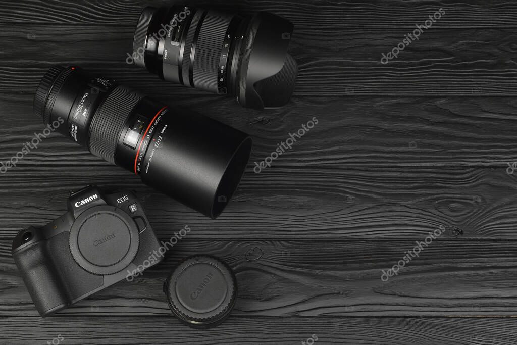 KHARKOV, UKRAINE - NOVEMBER 23, 2020: Canon EOS R photocamera and mount adapter EF - EOS R with Canon 105mm f2.8 and Sigma 24-105 f4 Art lenses on black wooden table