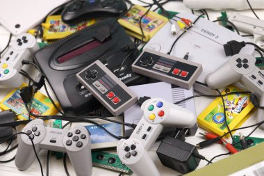 KHARKOV, UKRAINE - DECEMBER 27, 2020: Pile of old 8-bit video game consoles and many gaming accessories like a joysticks and cartridges. Old school retro gaming clipart