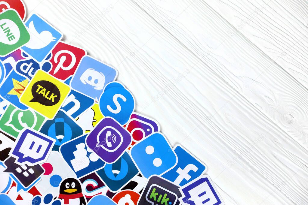 KHARKOV, UKRAINE - DECEMBER 26, 2020: Paper logos of most popular social networks and mobile messengers on wooden background. Facebook instagram youtube twitter tiktok twitch reddit and others