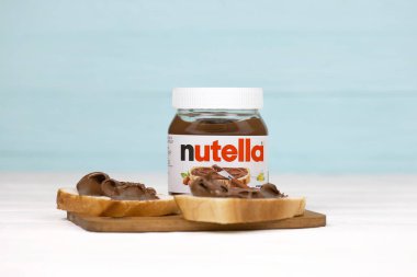 KHARKOV, UKRAINE - 27 Aralık 2020: Nutella cam kutu ve taze pişmiş ekmek üzerine yayılmış. Nutella, İtalyan Ferrero firması tarafından 1964 yılında üretilmiştir.