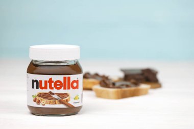 KHARKOV, UKRAINE - 27 Aralık 2020: Nutella cam kutu ve taze pişmiş ekmek üzerine yayılmış. Nutella, İtalyan Ferrero firması tarafından 1964 yılında üretilmiştir.
