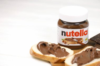 KHARKOV, UKRAINE - 27 Aralık 2020: Nutella cam kutu ve taze pişmiş ekmek üzerine yayılmış. Nutella, İtalyan Ferrero firması tarafından 1964 yılında üretilmiştir.