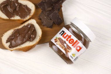 KHARKOV, UKRAINE - 27 Aralık 2020: Nutella cam kutu ve taze pişmiş ekmek üzerine yayılmış. Nutella, İtalyan Ferrero firması tarafından 1964 yılında üretilmiştir.