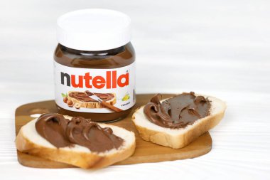 KHARKOV, UKRAINE - 27 Aralık 2020: Nutella cam kutu ve taze pişmiş ekmek üzerine yayılmış. Nutella, İtalyan Ferrero firması tarafından 1964 yılında üretilmiştir.