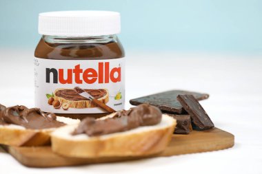 KHARKOV, UKRAINE - 27 Aralık 2020: Nutella cam kutu ve taze pişmiş ekmek üzerine yayılmış. Nutella, İtalyan Ferrero firması tarafından 1964 yılında üretilmiştir.