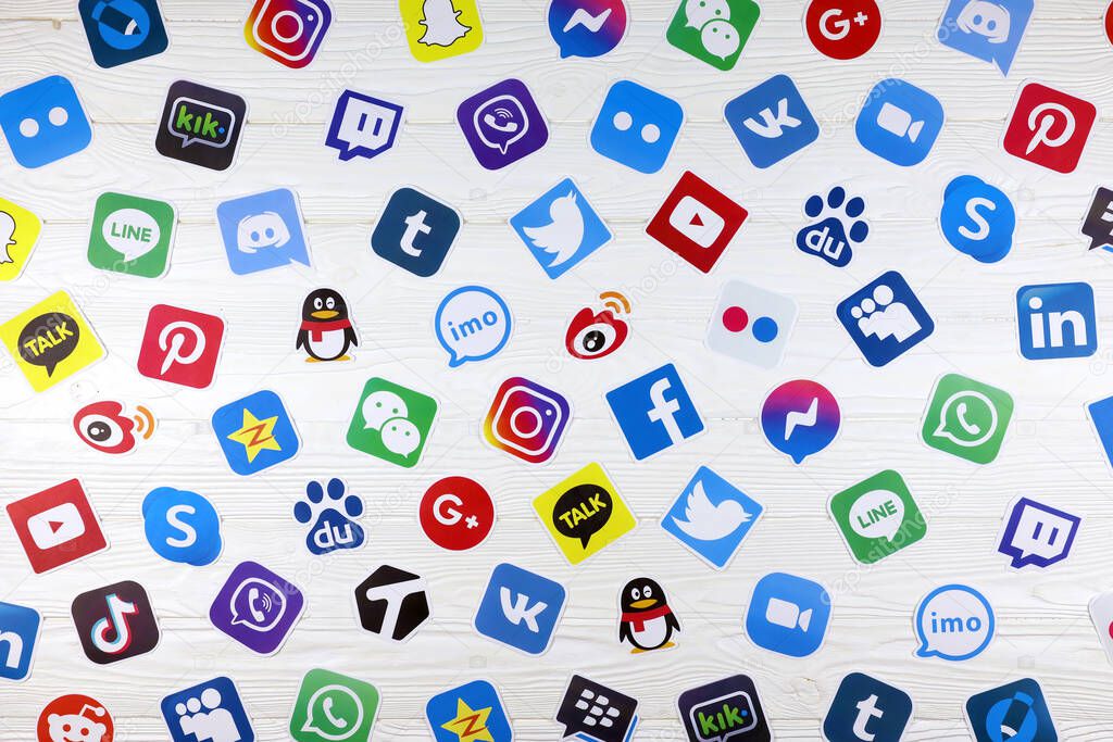 KHARKOV, UKRAINE - DECEMBER 26, 2020: Paper logos of most popular social networks and mobile messengers on wooden background. Facebook instagram youtube twitter tiktok twitch reddit and others