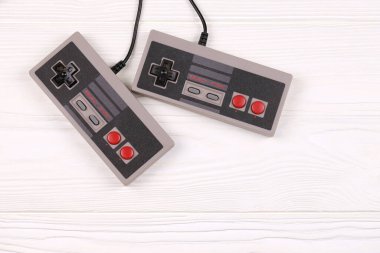 KHARKOV, UKRAINE - 27 Aralık 2020: 8-bit video oyun konsolları için iki eski oyun konsolu nintendo eğlence sistemi ve beyaz ahşap masa üzerinde nes mini. Eski moda oyun.