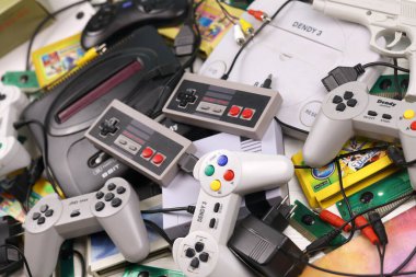 KHARKOV, UKRAINE - 27 Aralık 2020: Eski 8-bit video oyun konsolları ve joystick ve kartuşlar gibi birçok oyun aksesuarı yığını. Eski moda oyun.