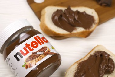 KHARKOV, UKRAINE - 27 Aralık 2020: Nutella cam kutu ve taze pişmiş ekmek üzerine yayılmış. Nutella, İtalyan Ferrero firması tarafından 1964 yılında üretilmiştir.
