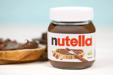 KHARKOV, UKRAINE - 27 Aralık 2020: Nutella cam kutu ve taze pişmiş ekmek üzerine yayılmış. Nutella, İtalyan Ferrero firması tarafından 1964 yılında üretilmiştir.