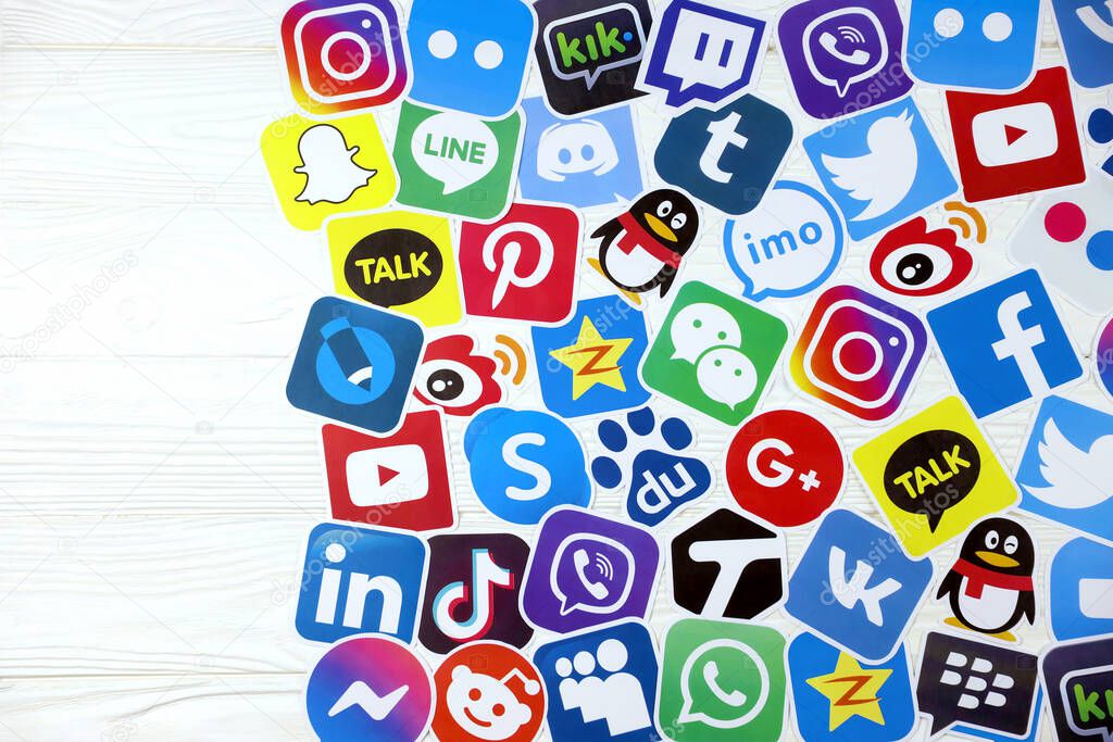 KHARKOV, UKRAINE - DECEMBER 26, 2020: Paper logos of most popular social networks and mobile messengers on wooden background. Facebook instagram youtube twitter tiktok twitch reddit and others