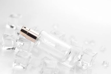 Kadın parfüm şişesi, buz küpleri ve su içinde parfüm şişesinin objektif fotoğrafı. Yukarıdan bak. ürün fotoğrafı, tazelik ve aroma konsepti