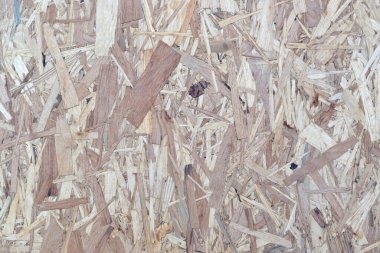 Kahverengi odun parçalarından yapılmış OSB tahtaları ahşap bir arka plana zımparalanmış. OSB tahta kaplama arkaplanının üst görünümü dar yüzeyler