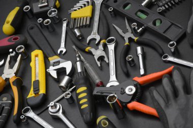 Siyah ahşap masada el işi alet çantası. Onarım ve inşaat işleri için birçok anahtar ve tornavida, sütun ve diğer aletler. Tamirci araçları ayarlandı