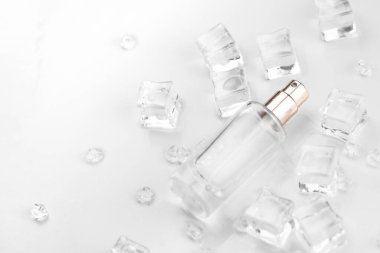 Kadın parfüm şişesi, buz küpleri ve su içinde parfüm şişesinin objektif fotoğrafı. Yukarıdan bak. ürün fotoğrafı, tazelik ve aroma konsepti