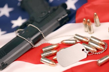 Many yellow 9mm bullets and gun with dogtags on United States flag. clipart