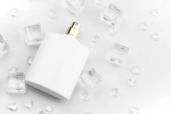 Female perfume mat white bottle, objective photograph of perfume bottle in ice cubes and water on white table. View from above. Mockup product photo, concept of freshness and aroma