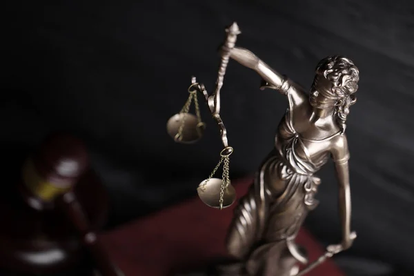 The Statue of Justice - lady justice or justitia the Roman goddess of Justice. Statue on brown book with judge gavel. Concept of judicial trial, courtroom process and lawyers occupation