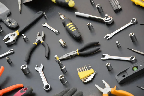 Siyah ahşap masada el işi alet çantası. Onarım ve inşaat işleri için birçok anahtar ve tornavida, sütun ve diğer aletler. Tamirci araçları ayarlandı