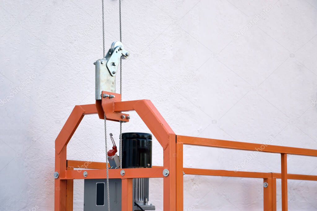 Hoist supply and safety lock as part of suspended wire rope platform for facade works on high multistorey buildings. Hoist for elevation, raising or lifting cradle platform