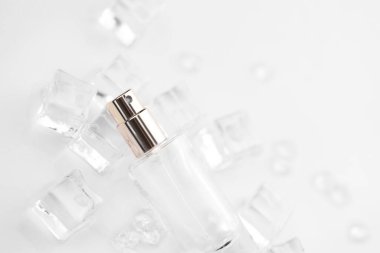 Kadın parfüm şişesi, buz küpleri ve su içinde parfüm şişesinin objektif fotoğrafı. Yukarıdan bak. ürün fotoğrafı, tazelik ve aroma konsepti