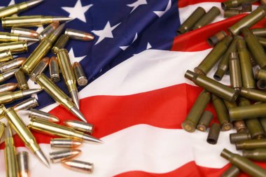 Many yellow 9mm and 5.56mm bullets and cartridges on United States flag. Concept of gun trafficking on USA territory or shooting range objects