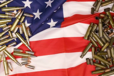 Many yellow 9mm and 5.56mm bullets and cartridges on United States flag. Concept of gun trafficking on USA territory or shooting range objects