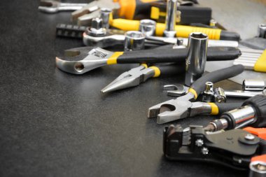 Siyah ahşap masada el işi alet çantası. Onarım ve inşaat işleri için birçok anahtar ve tornavida, sütun ve diğer aletler. Tamirci araçları ayarlandı