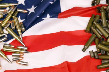 Many yellow 9mm and 5.56mm bullets and cartridges on United States flag. Concept of gun trafficking on USA territory or shooting range objects