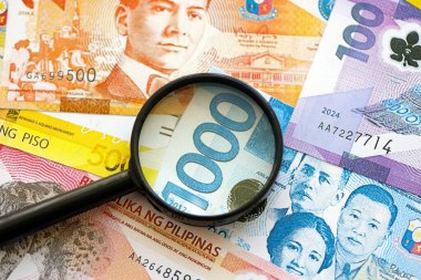 Filipinler Peso para birimi faturaları ve büyüteç yakın çekim. Finansal izleme ve vergilendirme kavramı