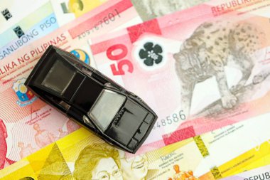 Filipinler Peso para birimi faturaları ve oyuncak araba. Araba sahibi olma kavramı.