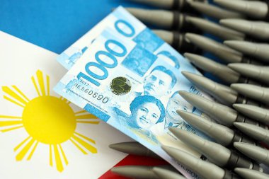 Filipinler para birimi banknotları ve bayraklar üzerinde tüfek mermileri. Savaş ve silah satışı kavramı