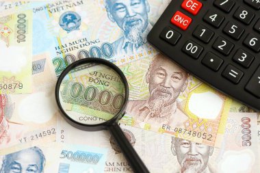 Vietnam dong para birimi faturaları ve büyüteçle yakınlaştırılmış hesap makinesi. Vergilendirme ve para sayımı kavramı