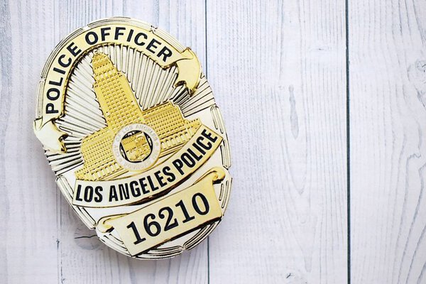 KYIV, UKRAINE - SEPTEMBER 17, 2025 US LAPD Police officer badge on white wooden table surface close up