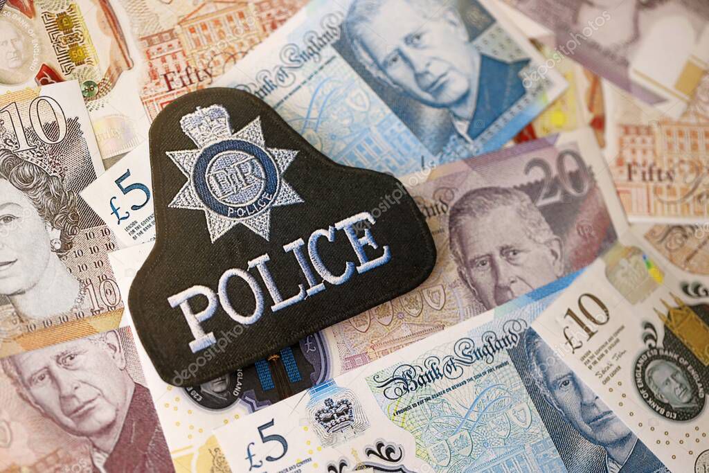 KYIV, UKRAINE - SEPTEMBER 17, 2025 United Kingdom Police badge on British pound money bills close up
