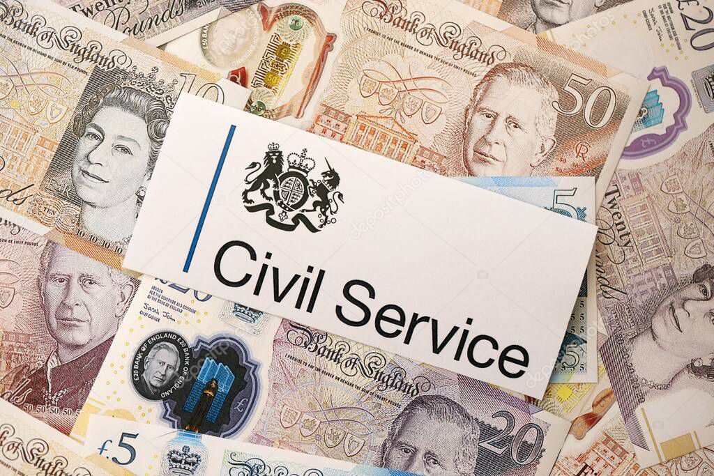 KYIV, UKRAINE - SEPTEMBER 17, 2025 UK Civil Service logotype sticker lies on British pounds money bills close up