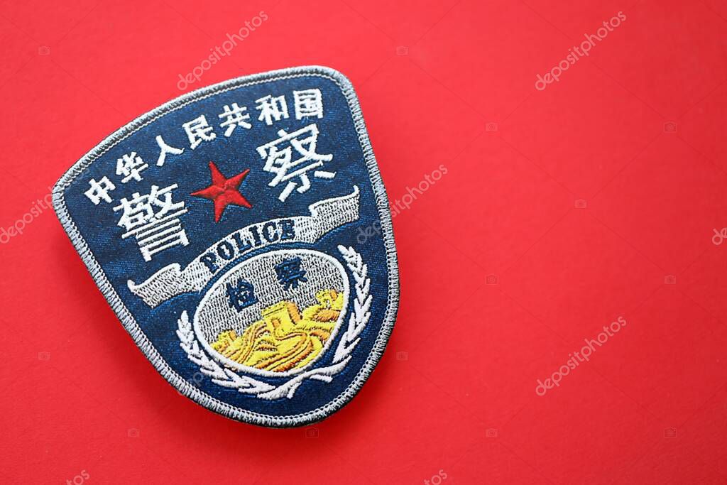KYIV, UKRAINE - SEPTEMBER 17, 2025 Chinese Police badge on national flag surface close up