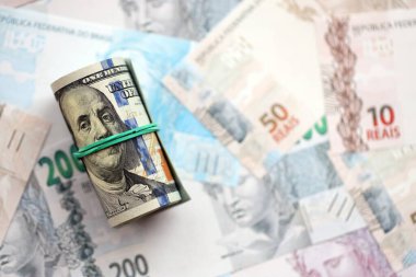 Bir tomar Amerikan doları büyük miktarda Brezilya banknotlarının üzerinde yatıyor. Amerikan parası Brezilya 'nın para akışında yatıyor. Brezilya 'da ekonomi ve döviz kuru kavramı